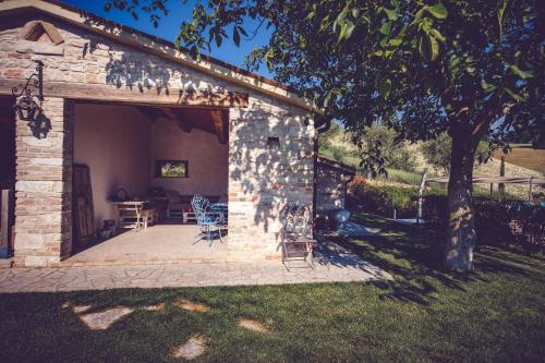 a stone building with a patio with chairs and a table at Agriturismo Casal San Sergio in Fossombrone