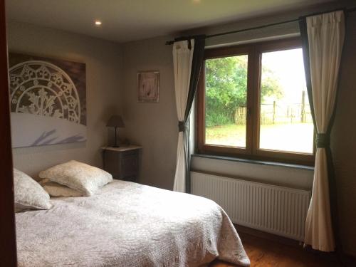 um quarto com uma cama e uma grande janela em La maison aux prés em Durbuy