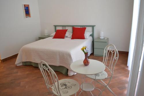 ナポリにあるLe Stanze di Dollyのベッドルーム1室(赤い枕のベッド1台、テーブル、椅子付)
