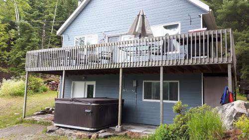 a house with a deck and an umbrella at Chalet Le Convivial Tremblant in Lac-Superieur