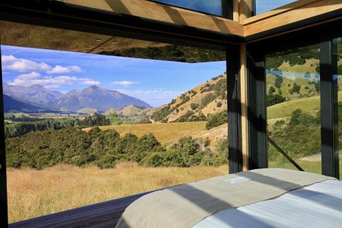 a bedroom with a view of the mountains through a window at Manakau PurePod in Kaikoura