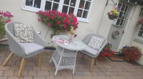 Tudor Farm B&B في Elston: كرسيين وطاولة على فناء مع زهور