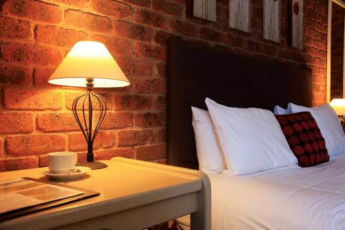 a bed with a lamp on top of it next to a wall at Admiral Motor Inn in Rosebud