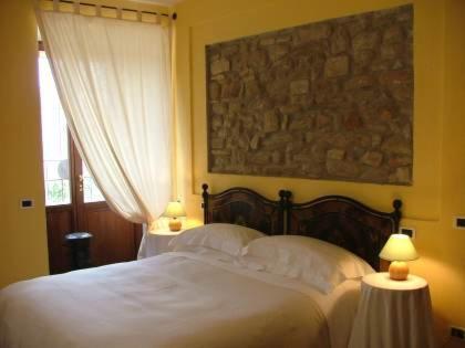a bedroom with a bed with white sheets and a window at Agriturismo Monastero Di San Biagio in Nocera Umbra