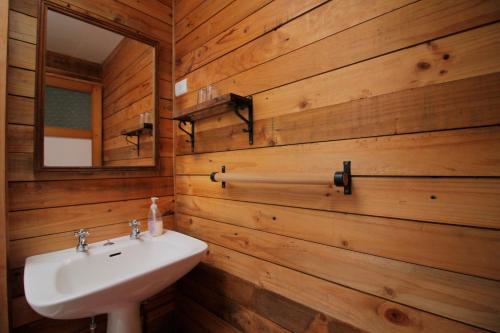 baño con paredes de madera, lavabo y espejo en Hotel Mi Casa, en Chaitén