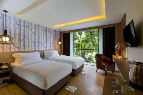 a hotel room with two beds and a window at GLOW Ao Nang Krabi in Ao Nang Beach