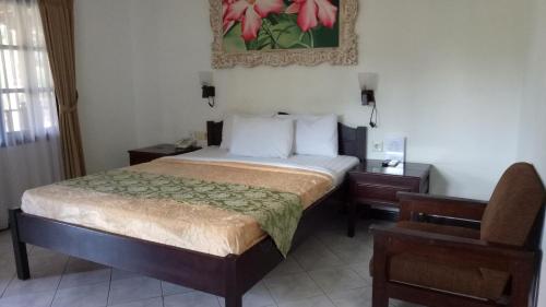 a hotel room with a bed and a chair at De Puspa Residence Seminyak in Seminyak