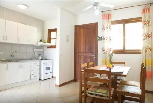 una cocina con mesa y sillas y una cocina con armarios blancos. en Apartamento em Residencial Riviera, en Florianópolis