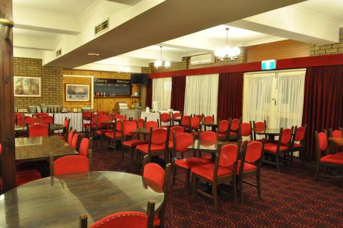 a dining room with tables and red chairs at Albury Burvale Motor Inn in Albury