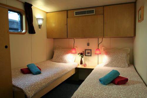 two beds in a small room with a desk at Hotelboat Fleur in Amsterdam