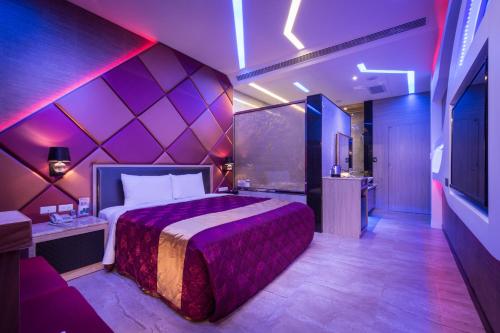 1 dormitorio con 1 cama con pared morada en OUGE Boutique Motel - Pingtung en Jiuru