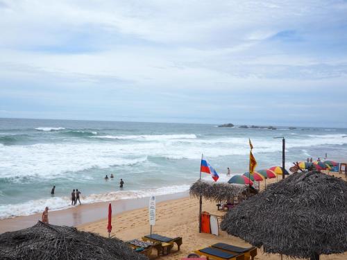a beach with people in the ocean and waves at Main Reef Guest House in Hikkaduwa