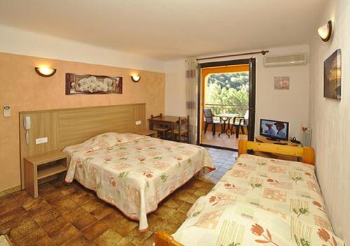 SerrieraにあるRésidence Cabanacciaのベッド2台とバルコニーが備わるホテルルームです。