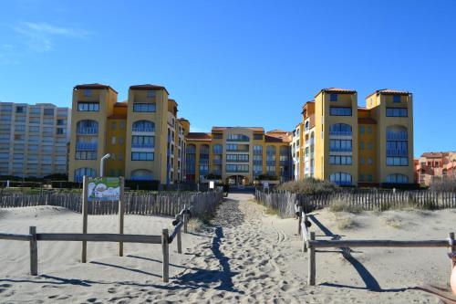 a beach with buildings and benches in the sand at Appartement Romantic Sea in Le Barcarès