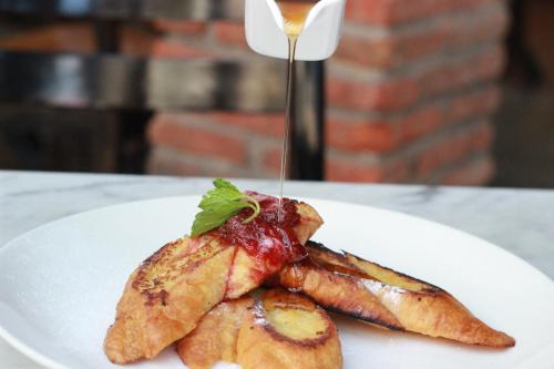 a white plate with a piece of food with a sauce at Ossotel Legian in Legian
