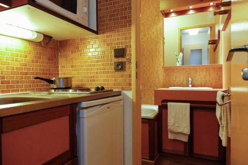 eine kleine Küche mit einem Waschbecken und einem Spiegel in der Unterkunft Résidence Odalys Tourotel in Val Thorens