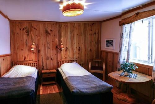 a bedroom with two beds and a table and a window at STF Hotel & Hostel Persåsen in Persåsen