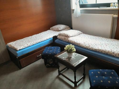 two beds in a room with a table and chairs at Pokoje Gościnne z łazienkami przy Wrocławiu, darmowy parking in Długołęka