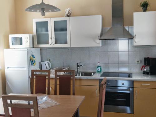 cocina con nevera blanca, mesa y sillas en Apartments Kristina, en Klenovica