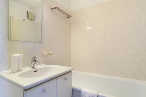 a white bathroom with a sink and a bath tub at Résidence Odalys Les Hauts de Balaruc in Balaruc-les-Bains