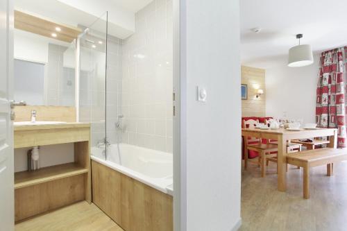 ein Badezimmer mit einer Badewanne und ein Esszimmer in der Unterkunft Résidence Goélia Le Crystal in Vaujany