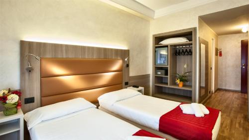 a hotel room with two beds and a closet at Hotel Gamma in Milan