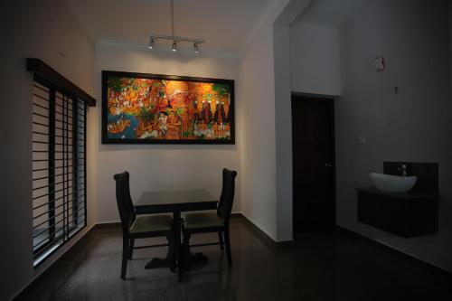a dining room with a table and a painting on the wall at Anchorage Serviced Apartments in Cochin