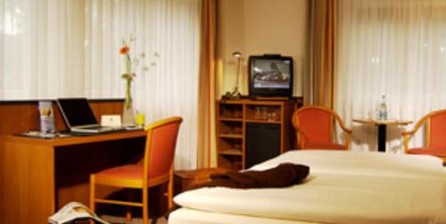 a hotel room with a bed and a desk and a television at Andersen Hotel Schwedt in Schwedt