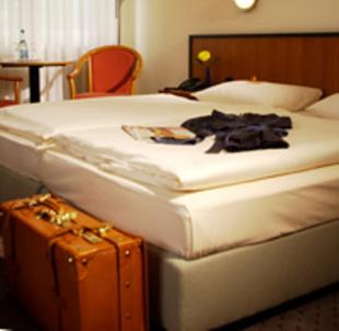 シュヴェットにあるAndersen Hotel Schwedtのベッドとスーツケース付きのホテルルーム