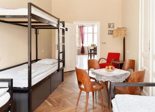 
a bedroom with a bed, table and chairs at Hostel Fleda in Brno
