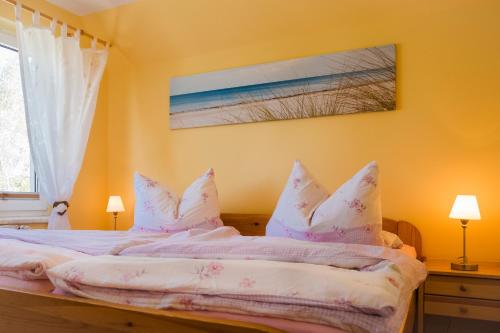 Schlafzimmer mit einem Bett mit weißer Bettwäsche und Kissen in der Unterkunft Naturidyll auf Rügen in Putbus