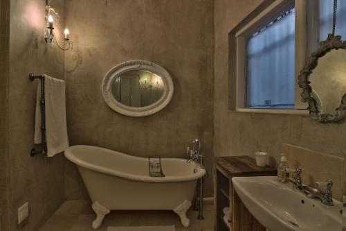 a bathroom with a tub and a sink and a mirror at Dar El Hout in Hout Bay
