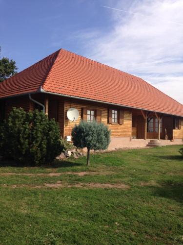 una casa de madera con un árbol delante en Mézesfészer apartman, en Cserkút