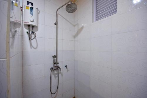 a shower in a white tiled bathroom with a shower at Beach Villa Ukulhas in Ukulhas