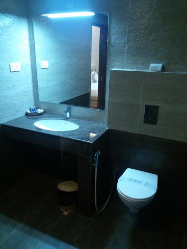 a bathroom with a sink and a toilet and a mirror at Shivaprasad Grand in Kundapur