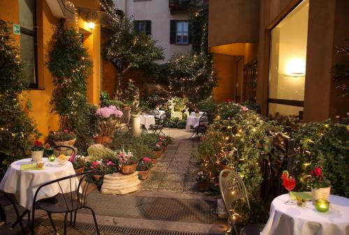 restauracja ze stołami i kwiatami na dziedzińcu w obiekcie Hotel Sanpi Milano w Mediolanie