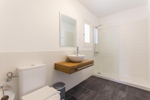 a white bathroom with a sink and a toilet at Apartamento Gama in Cala Galdana