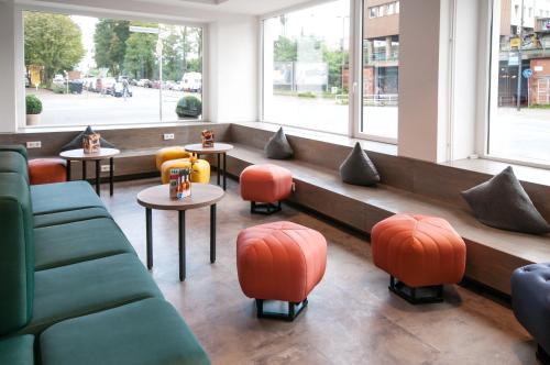 a restaurant with orange and green chairs and tables at a&o Bremen Hauptbahnhof in Bremen