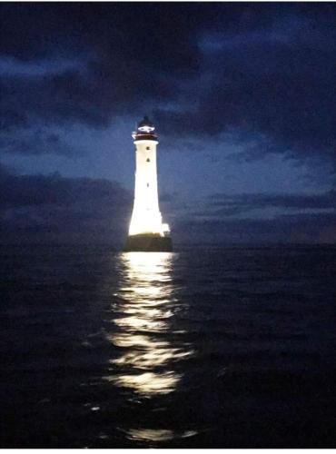 a lighthouse sitting in the water at night at Greencastle B&B in Kilkeel