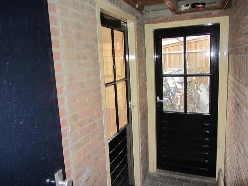 a black door with a window in a brick wall at Holiday Home Emmastraat in Katwijk