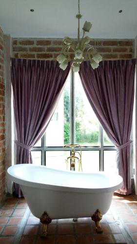 a bath tub in a room with a window at Stamp Hills Resort in Suan Phung