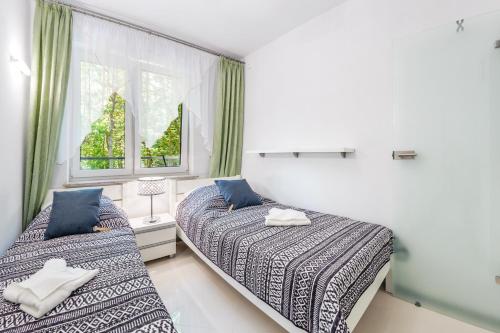 a bedroom with two beds and a window at Dwie Sosny z sauną, Sun & Snow in Ustronie Morskie