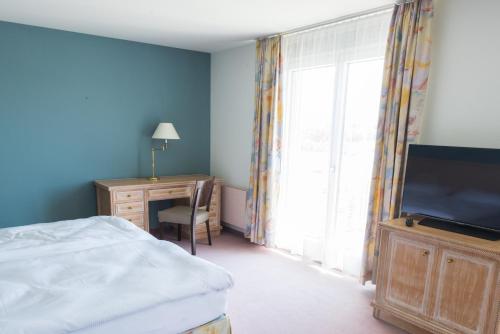 a bedroom with a bed and a desk and a television at Ascott Hotel & Restaurant in Rombach