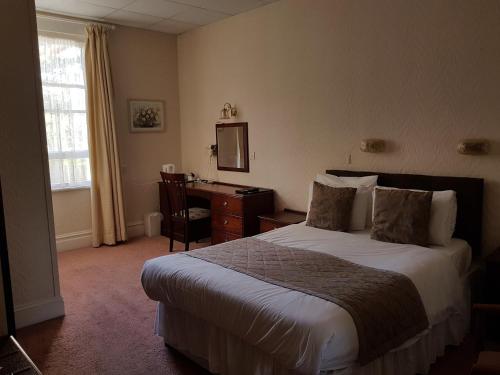 a bedroom with a bed and a dresser at Burley Court Hotel in Bournemouth