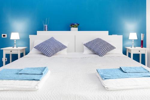 a white bed with two blue pillows and towels on it at B&B Cozy Cove in Torre del Greco