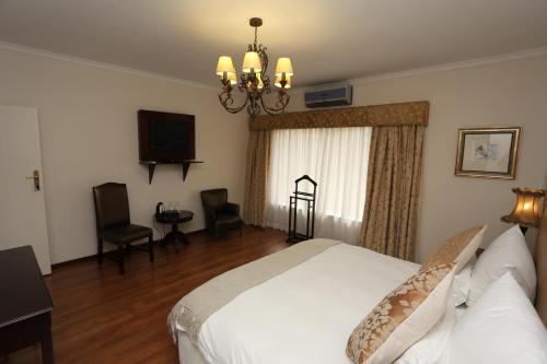 a bedroom with a white bed and a television at Villa Moringa Guesthouse in Windhoek