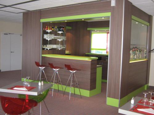 a bar in a restaurant with red stools at ibis Styles Saint Dizier in Saint-Dizier