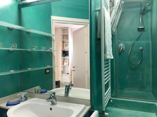 bagno con pareti verdi, lavandino e doccia di Appartamento Porta Saragozza a Bologna