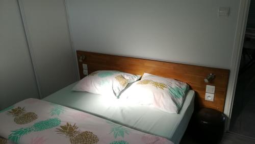 ein Bett mit einem Kopfteil aus Holz und zwei Kissen in der Unterkunft Le Tiot Gîte in Le Bois de Cise