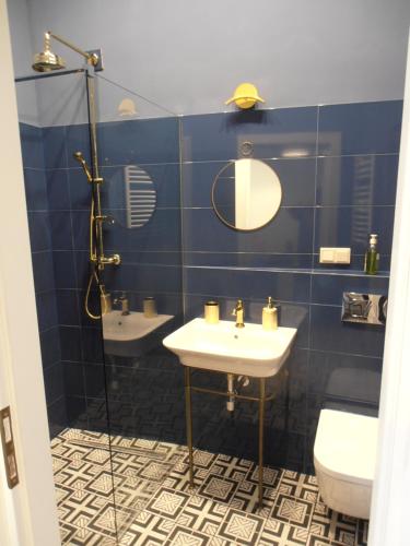 - une salle de bains carrelée de bleu avec lavabo et 2 toilettes dans l'établissement Apartamenty Rudi, à Cracovie